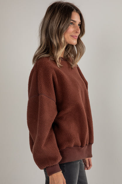 Woman wearing a brown fleece sweater against a plain background