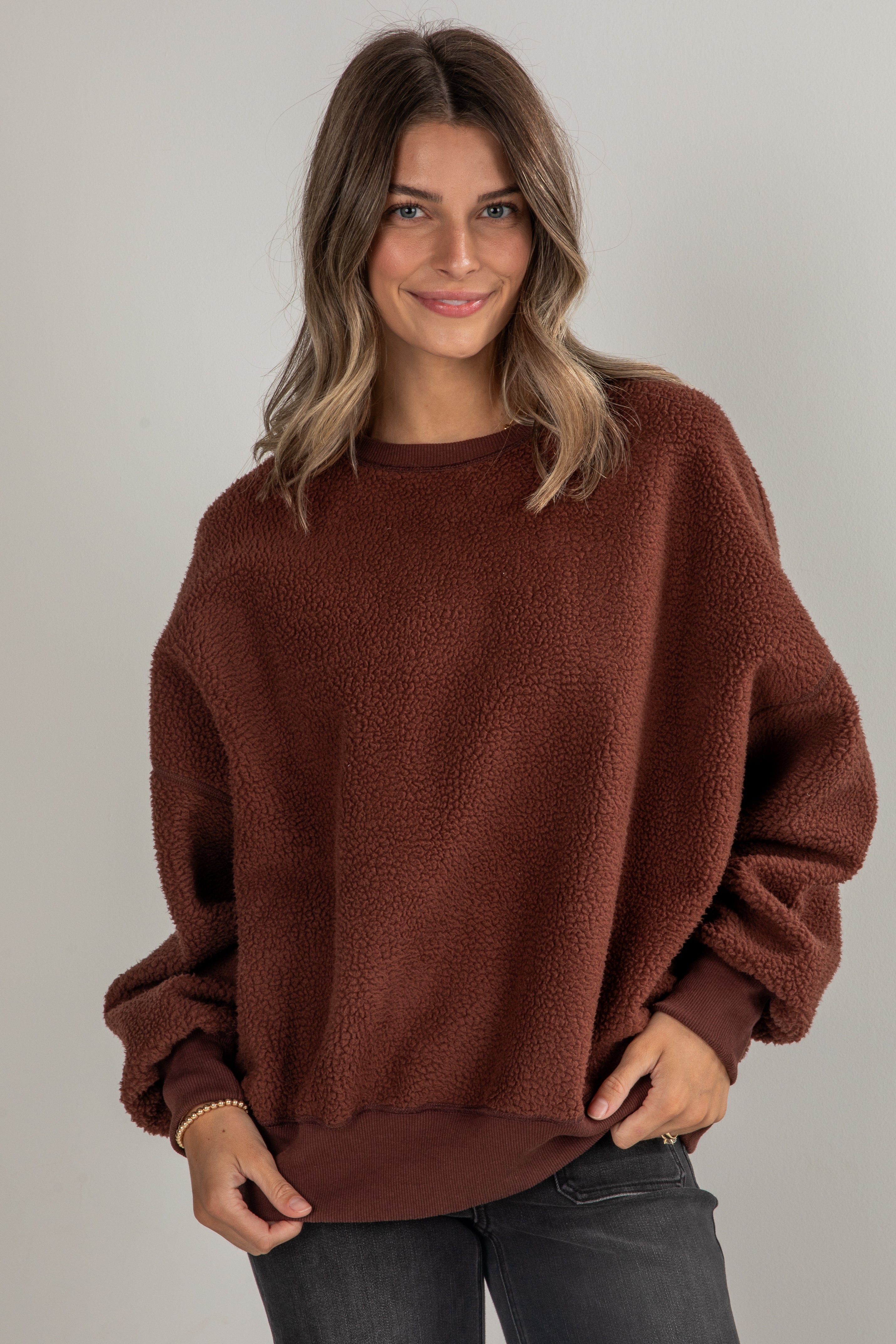 Woman wearing a brown sweater against a plain background