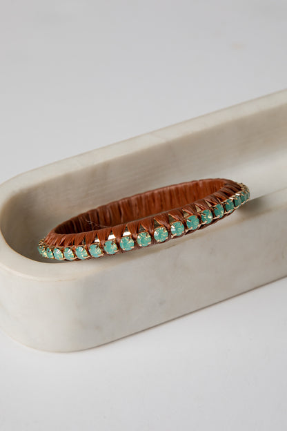 Bracelet with turquoise stones on a beige dish against a white background