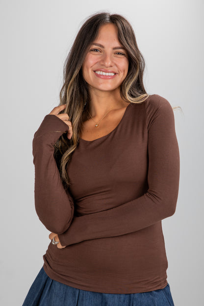 Woman wearing a brown long-sleeve top against a plain background
