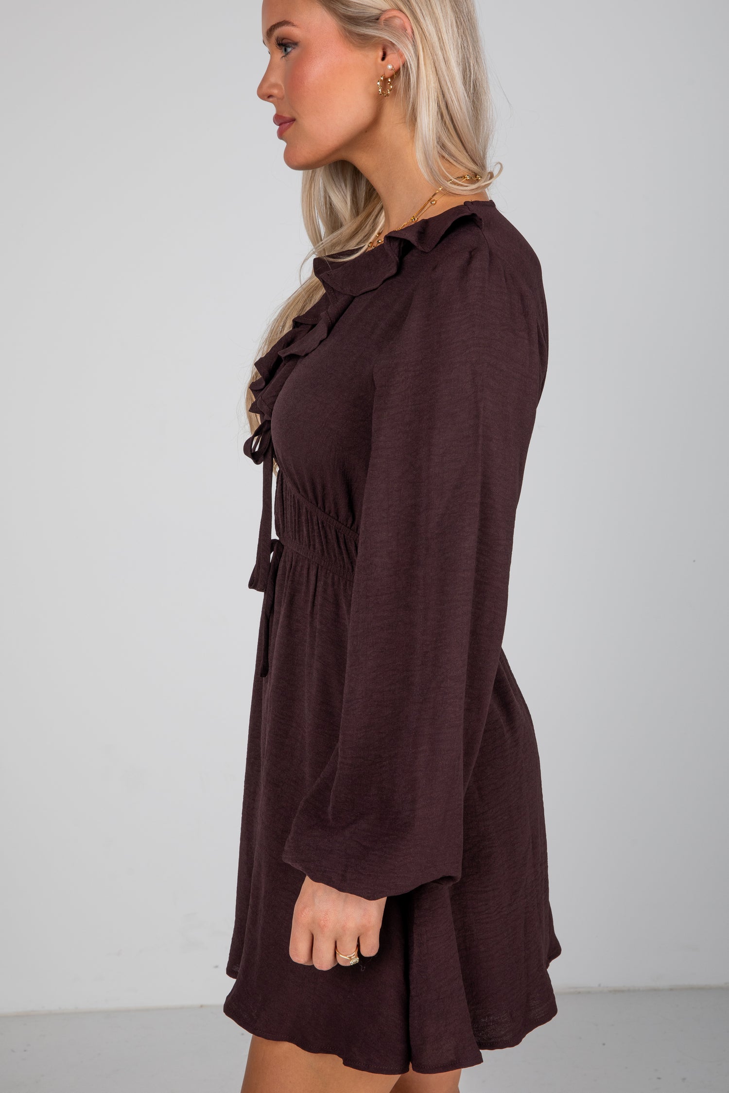 Woman wearing a brown dress against a plain background