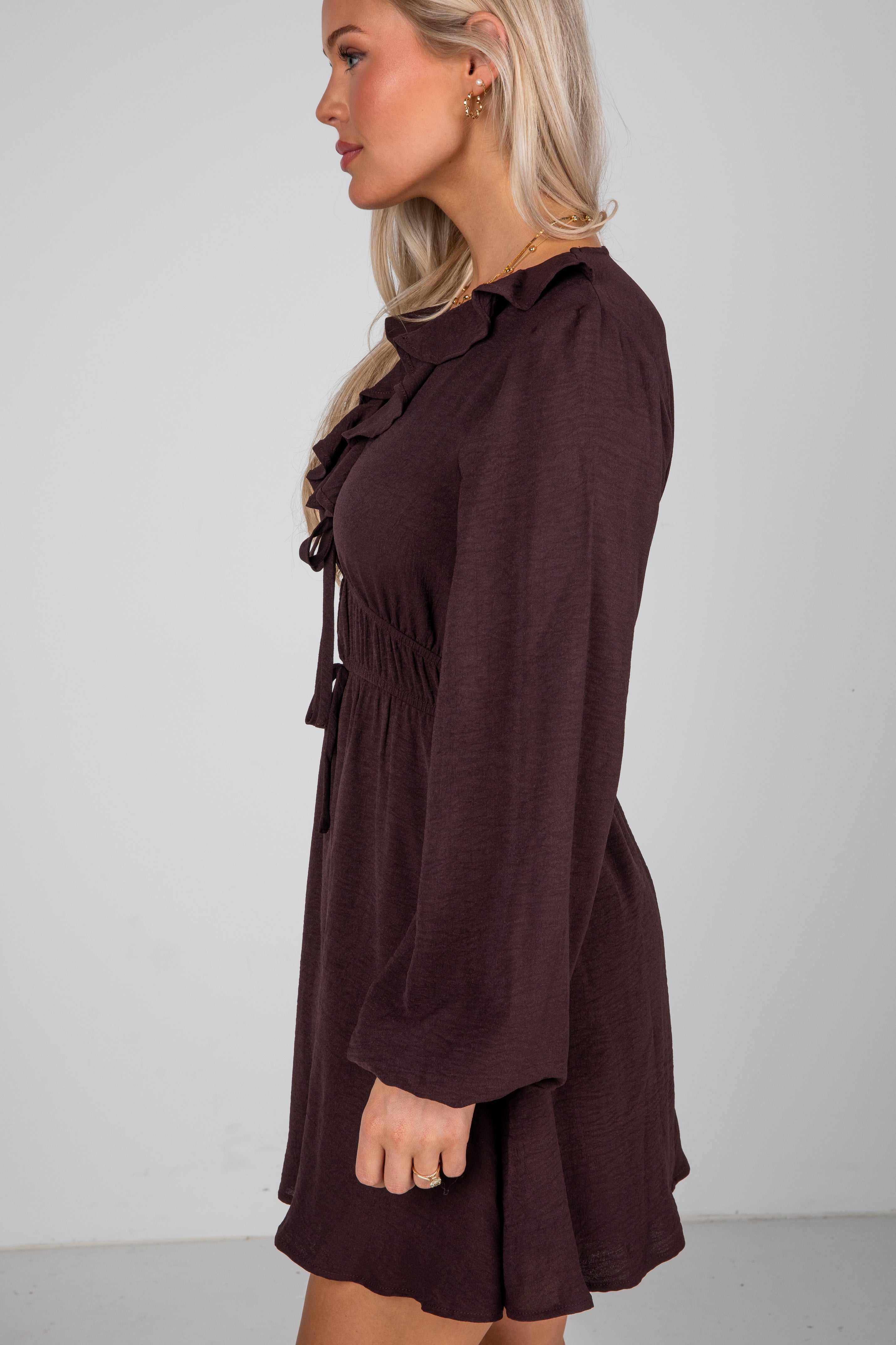 Woman wearing a brown dress against a plain background