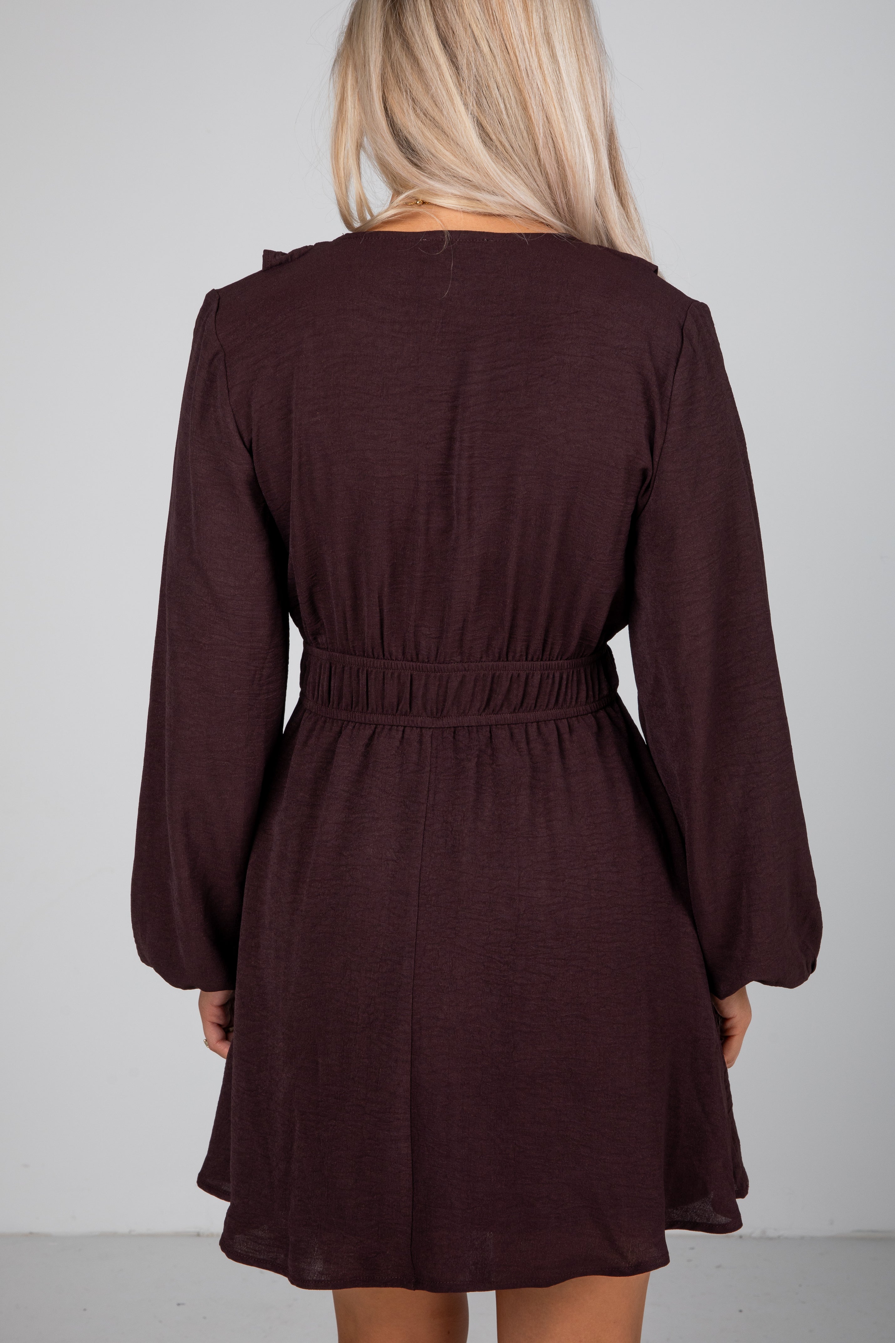 Brown dress with long sleeves and a belt on a plain background