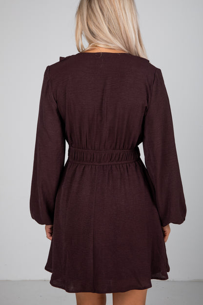Brown dress with long sleeves and a belt on a plain background