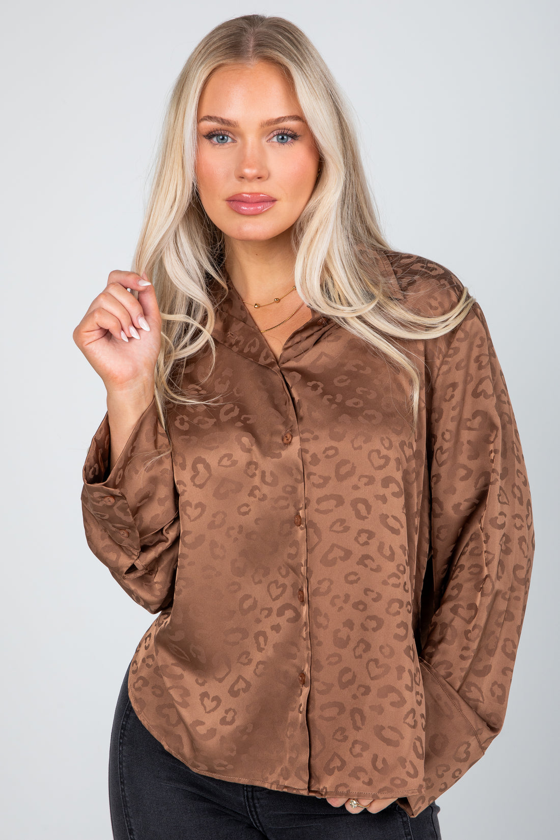 Woman wearing a brown leopard print blouse against a plain background