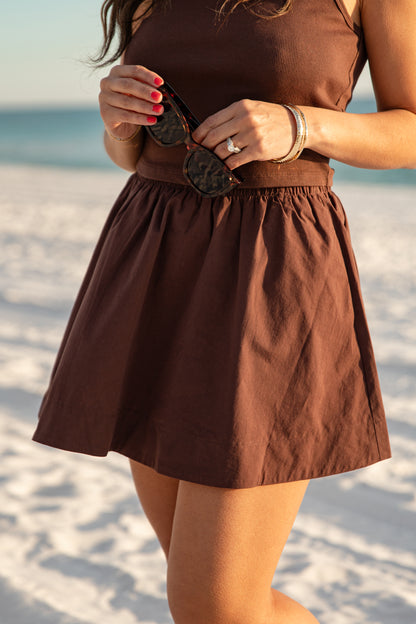 Person wearing a brown skirt on a sandy beach