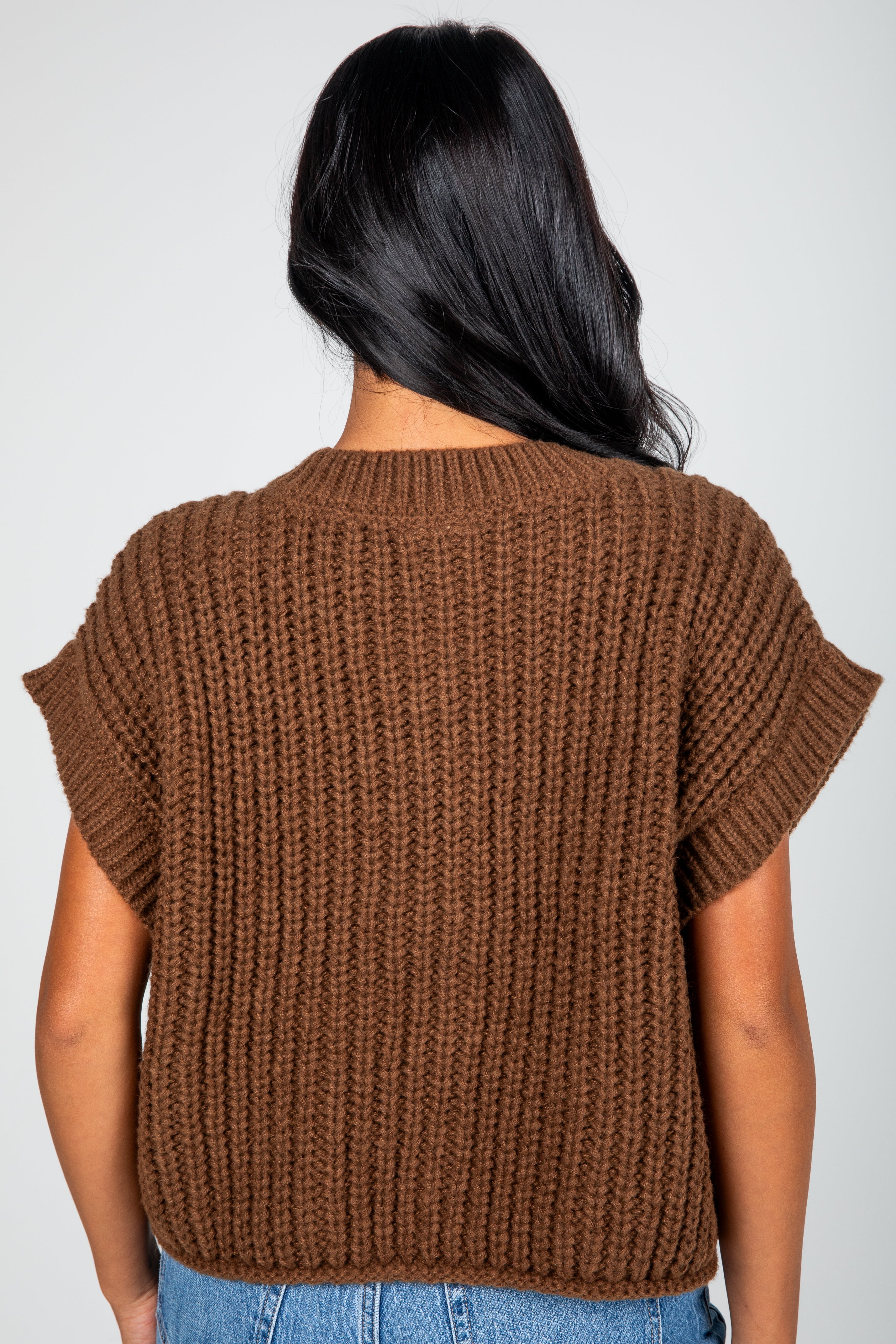 Brown knitted top worn by a person on a plain background