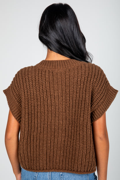 Brown knitted top worn by a person on a plain background