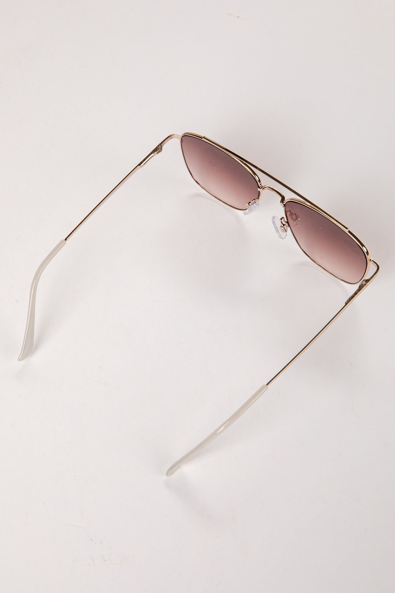 Gold-framed sunglasses with pink lenses on a white background
