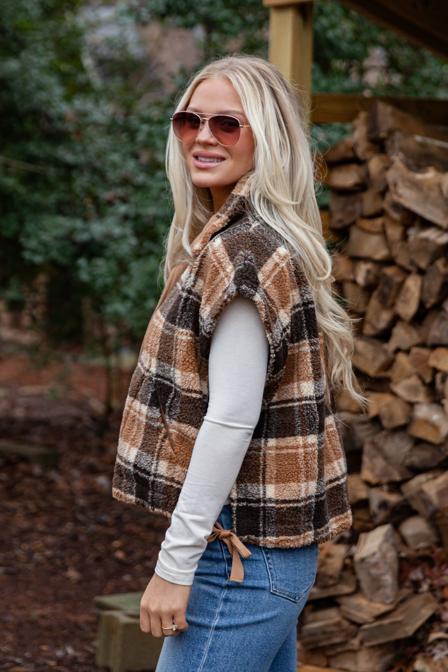 Woman wearing a plaid vest in a forest setting