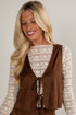 Woman wearing a brown vest over a patterned top against a plain background
