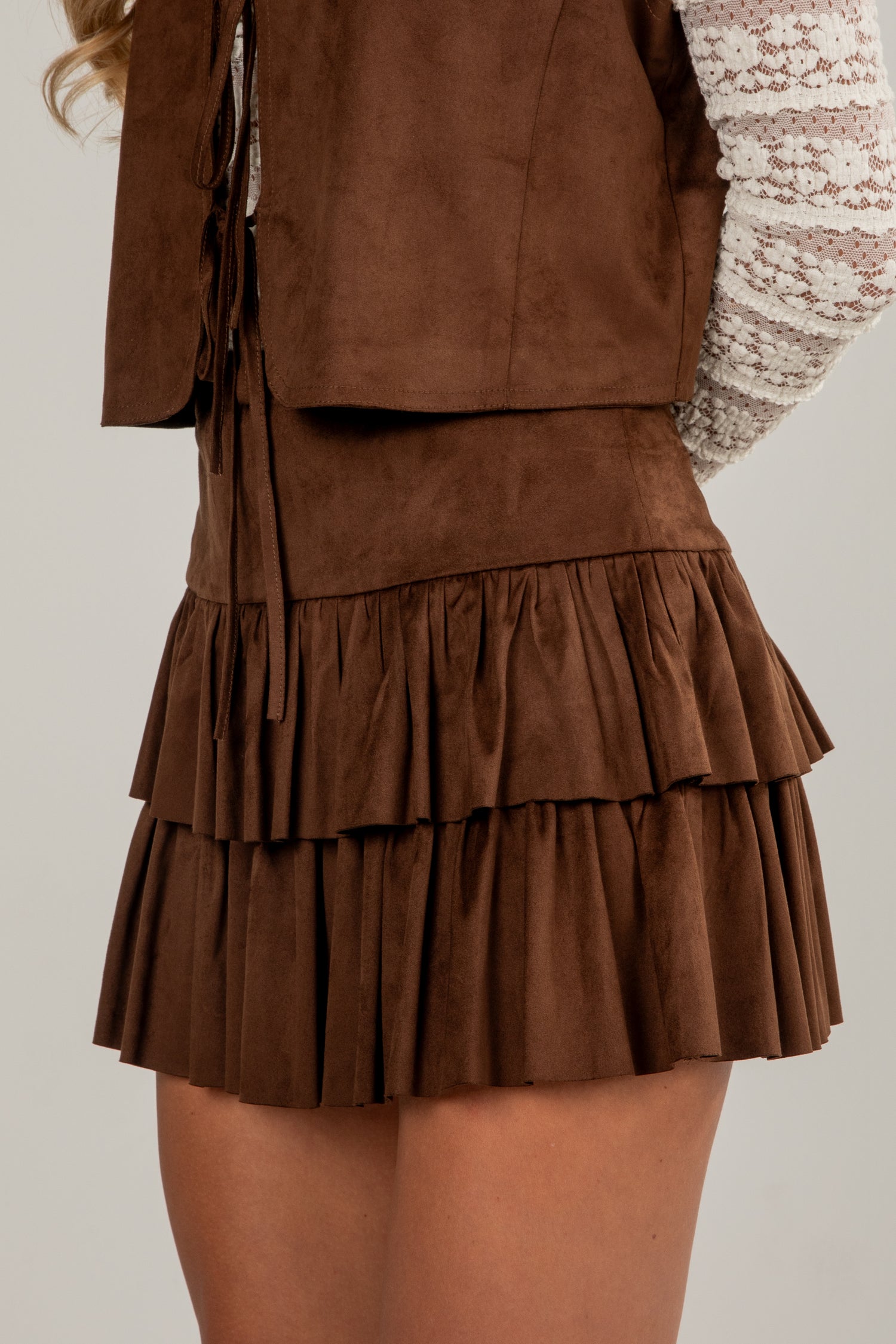 Brown suede skirt with ruffled layers on a neutral background