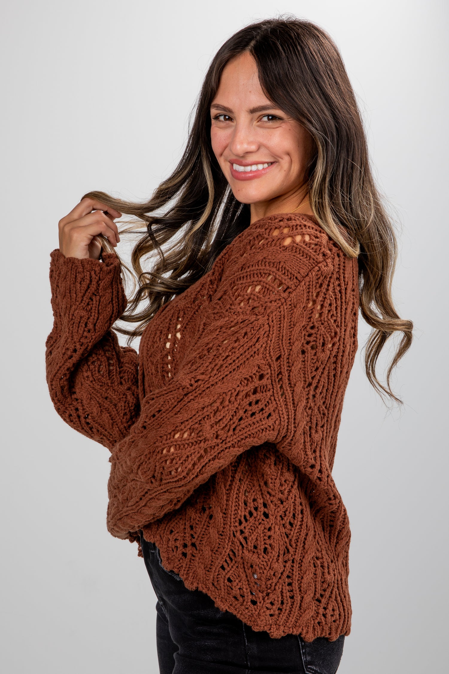 Woman wearing a brown knitted sweater against a white background