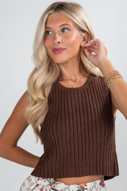 Woman wearing a brown ribbed tank top against a plain background