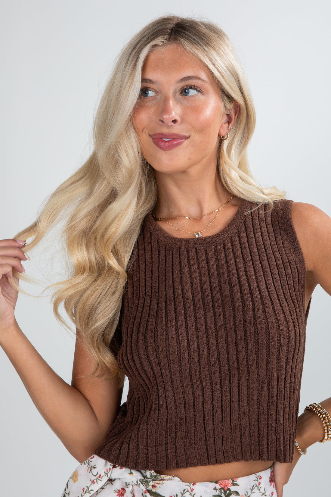 Woman wearing a brown ribbed tank top against a plain background