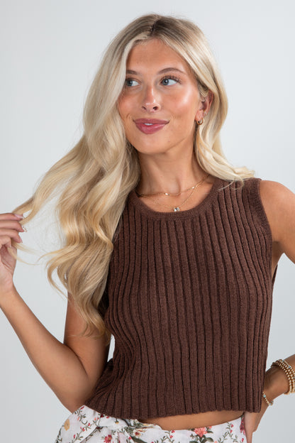 Woman wearing a brown ribbed tank top against a plain background