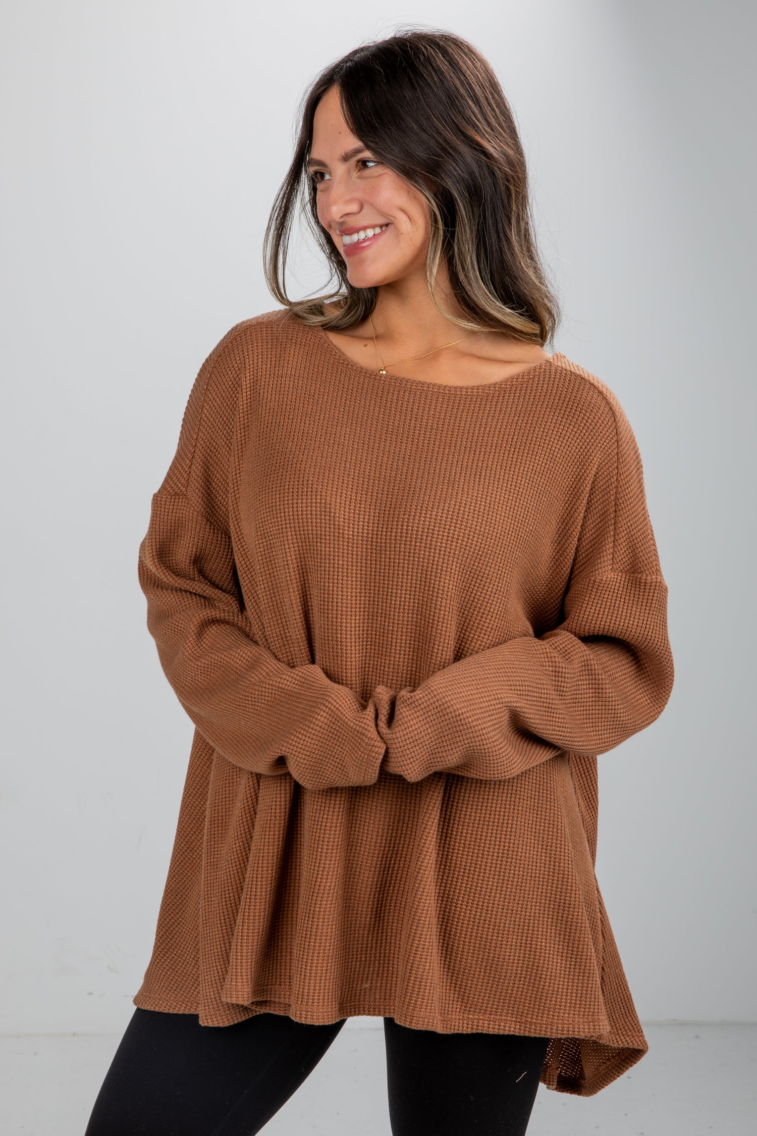 Woman wearing a brown sweater against a white background
