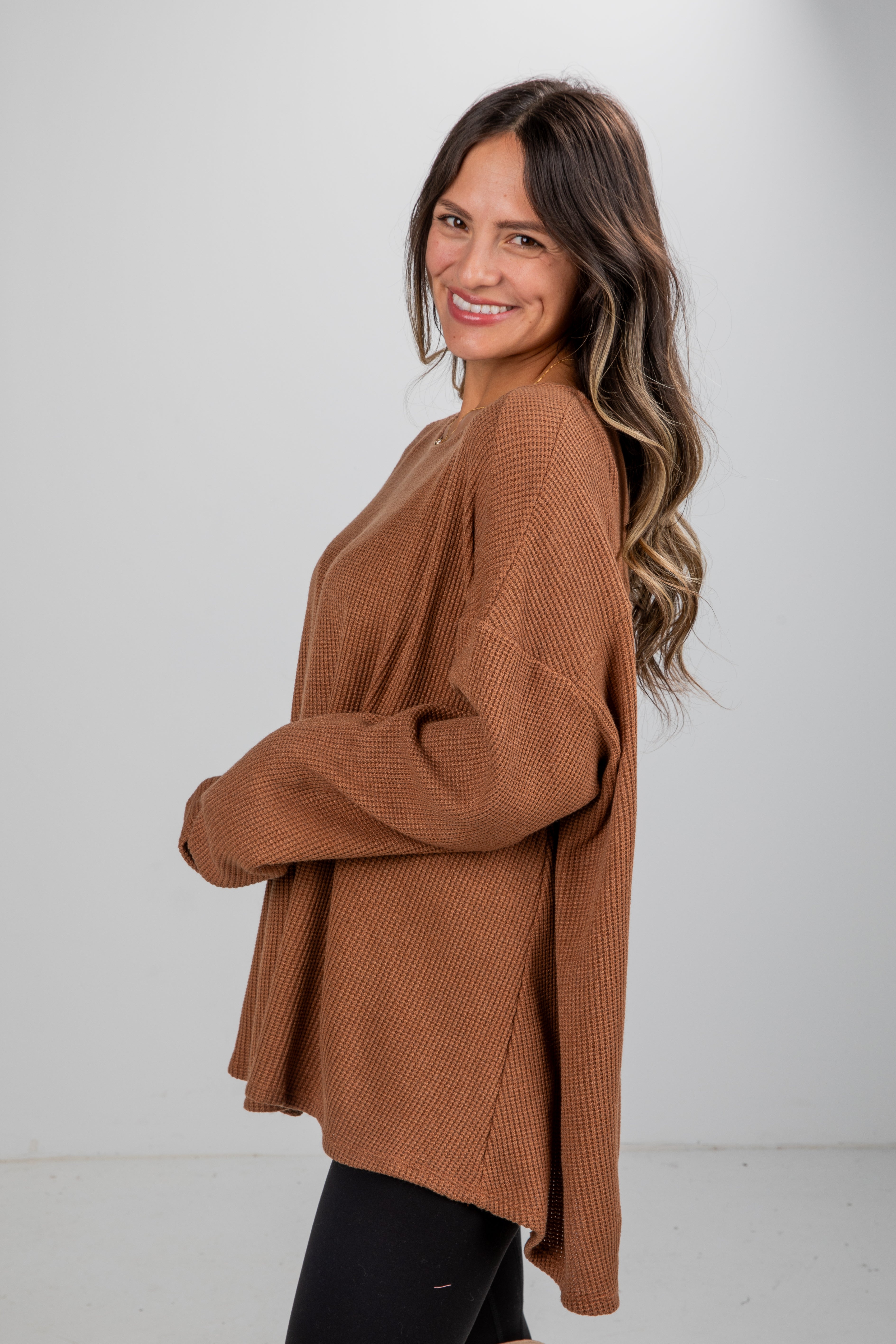 Woman wearing a brown sweater against a white background