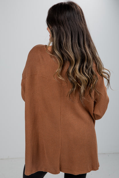 Person wearing a brown cardigan against a white background