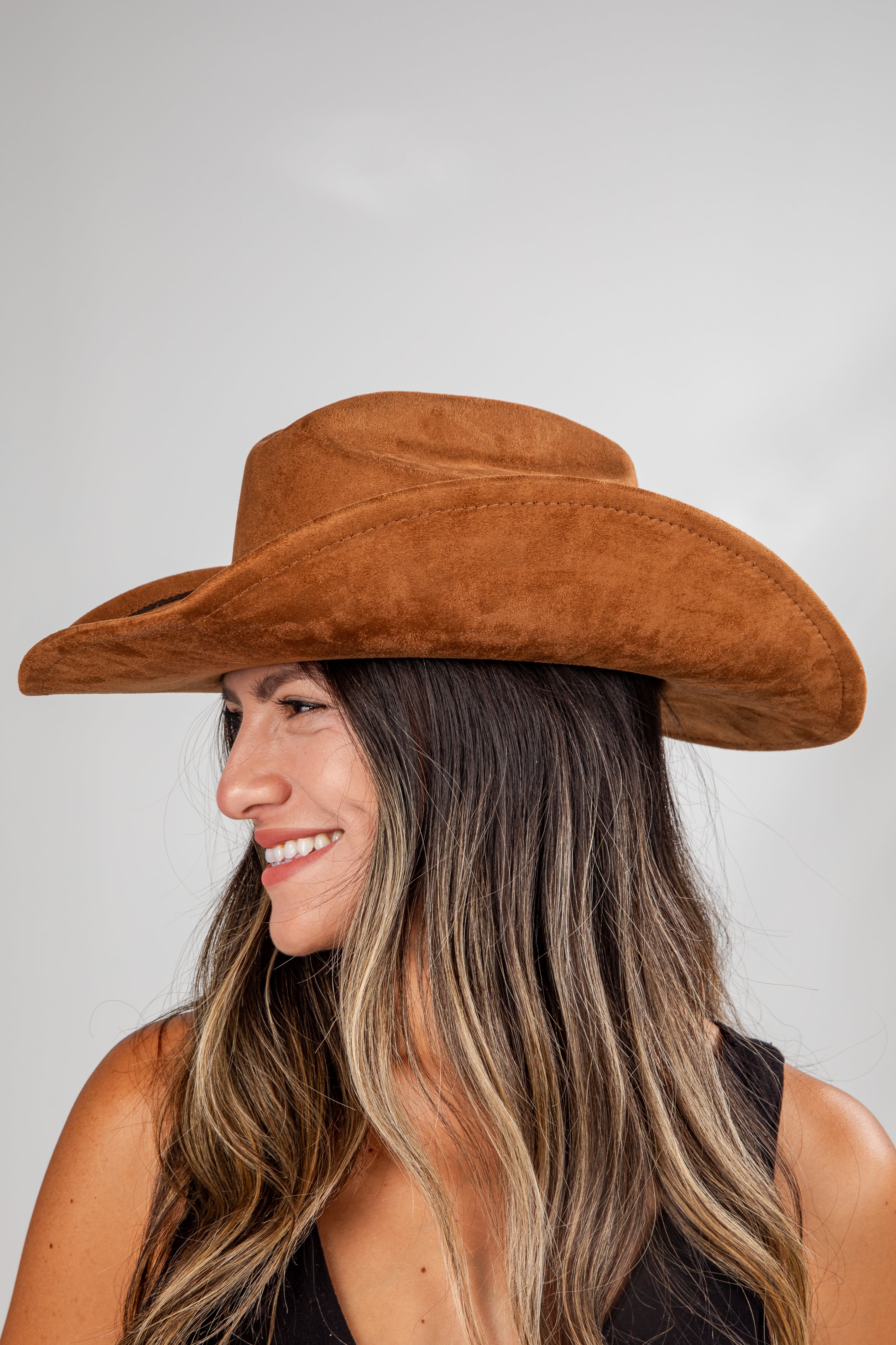 Woman wearing a brown cowboy hat against a plain background