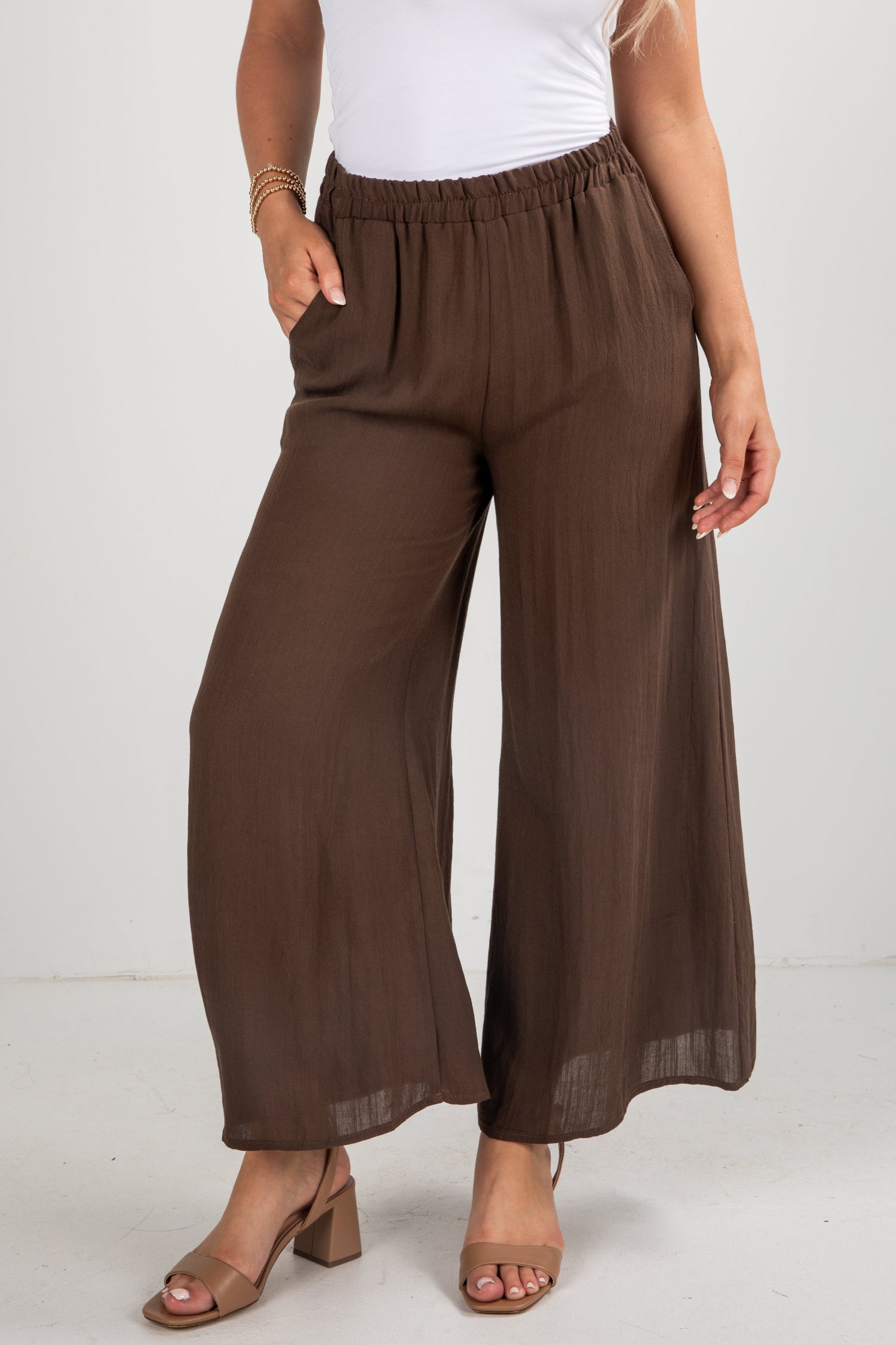 Brown wide-leg pants worn by a person on a white background