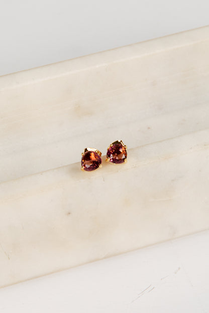Pair of red gemstone stud earrings on a beige surface