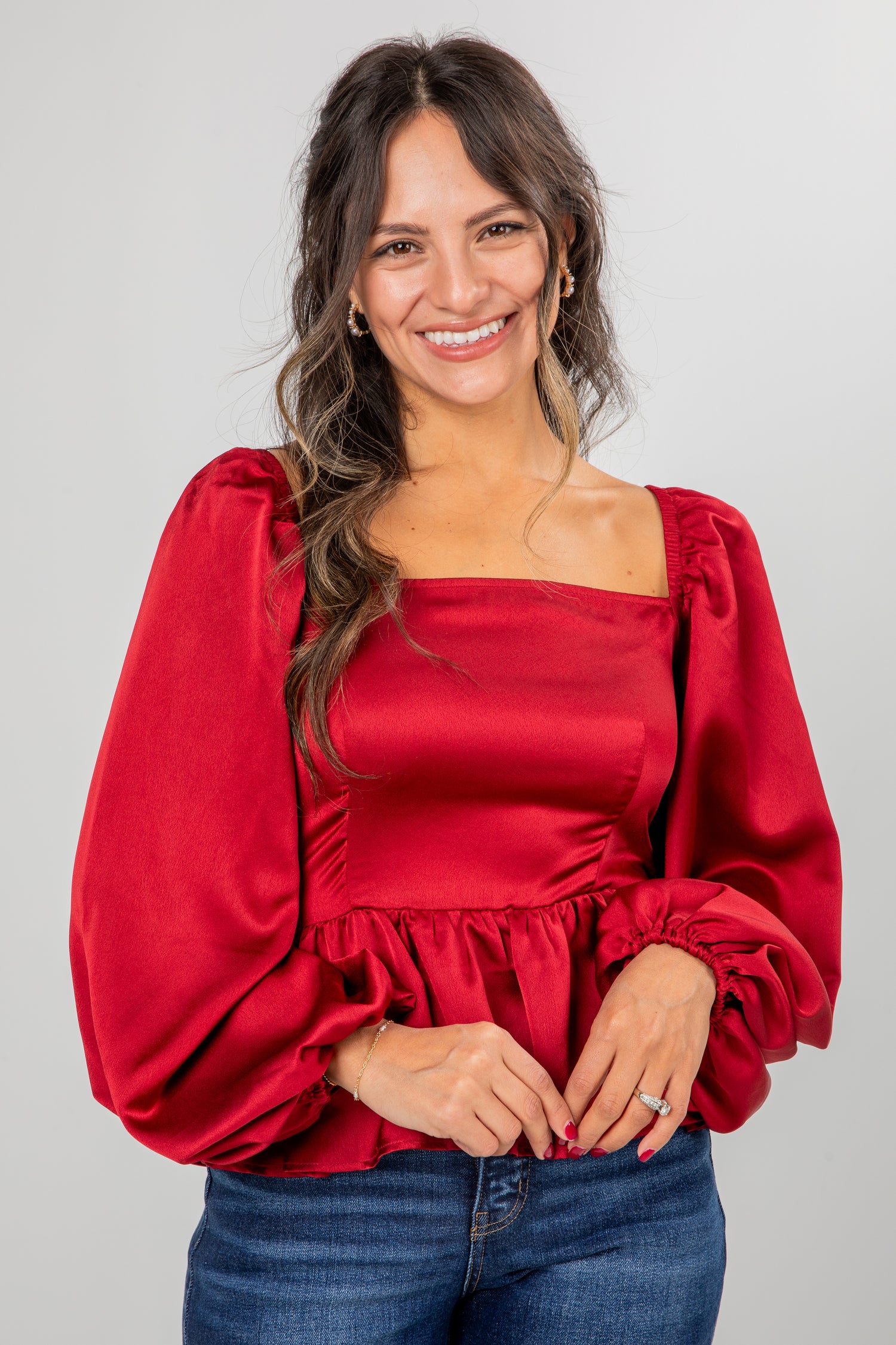 Woman wearing a red blouse with puffed sleeves on a gray background