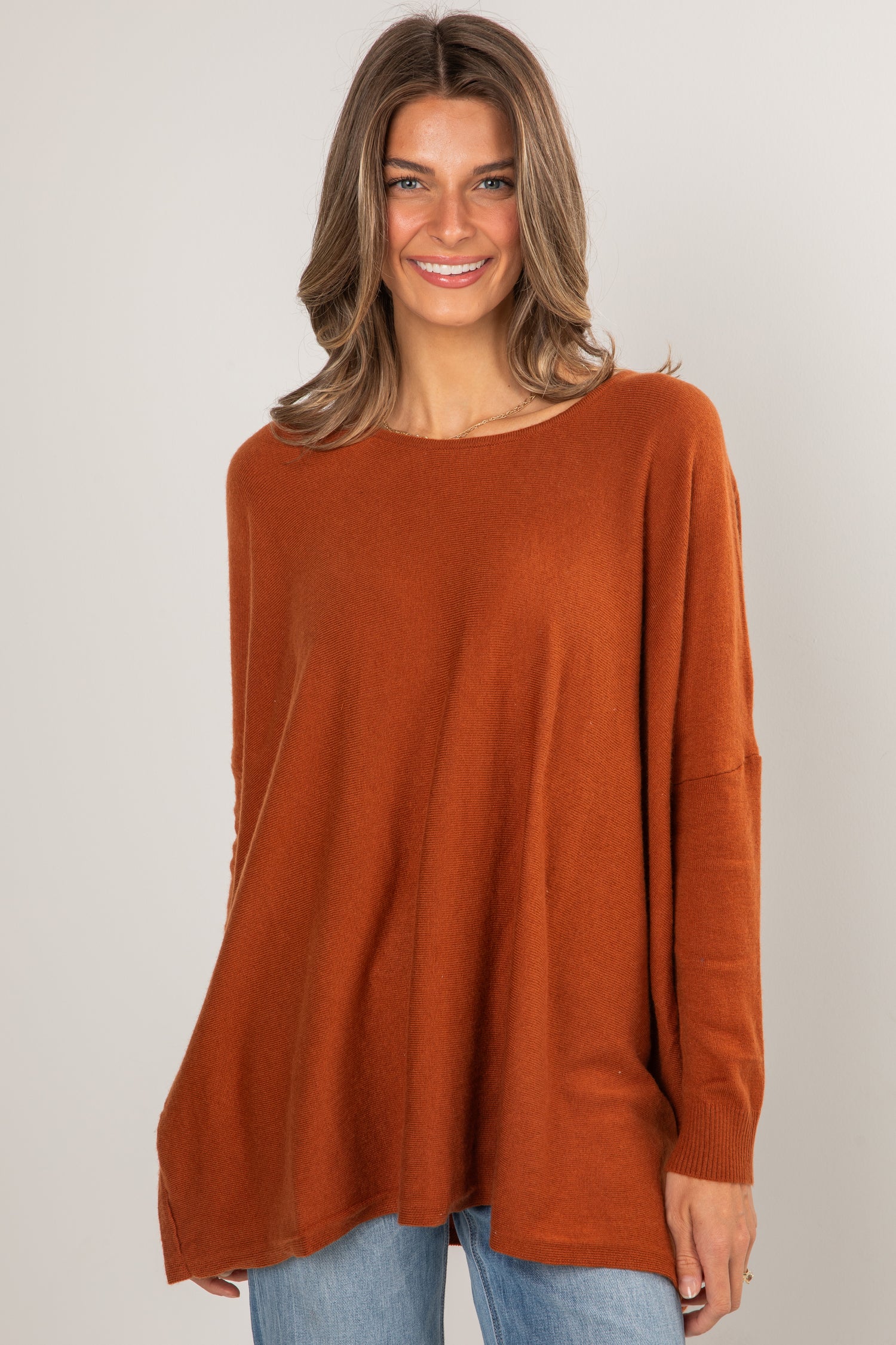 Woman wearing a rust-colored sweater against a plain background