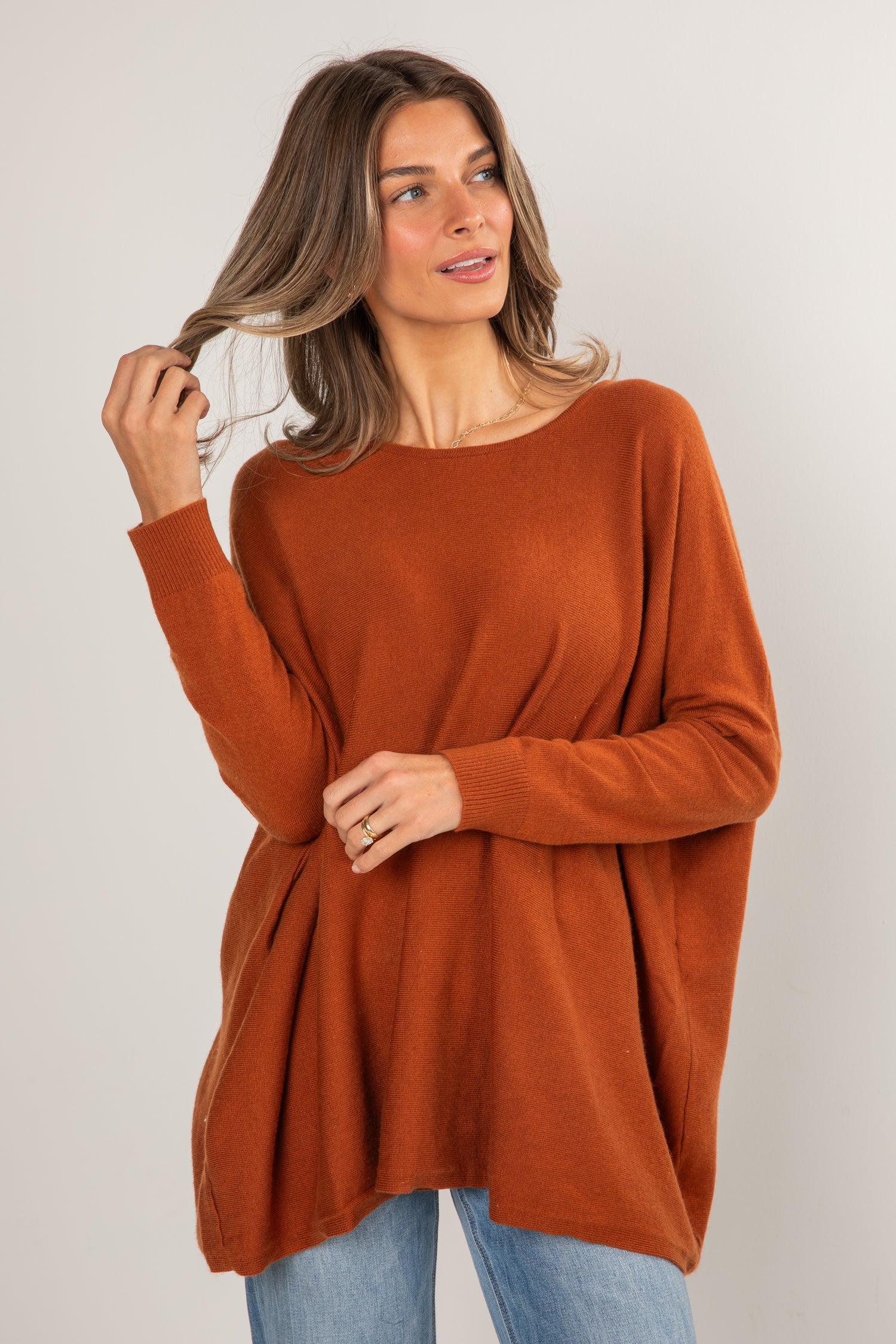 Woman wearing a rust-colored sweater against a plain background