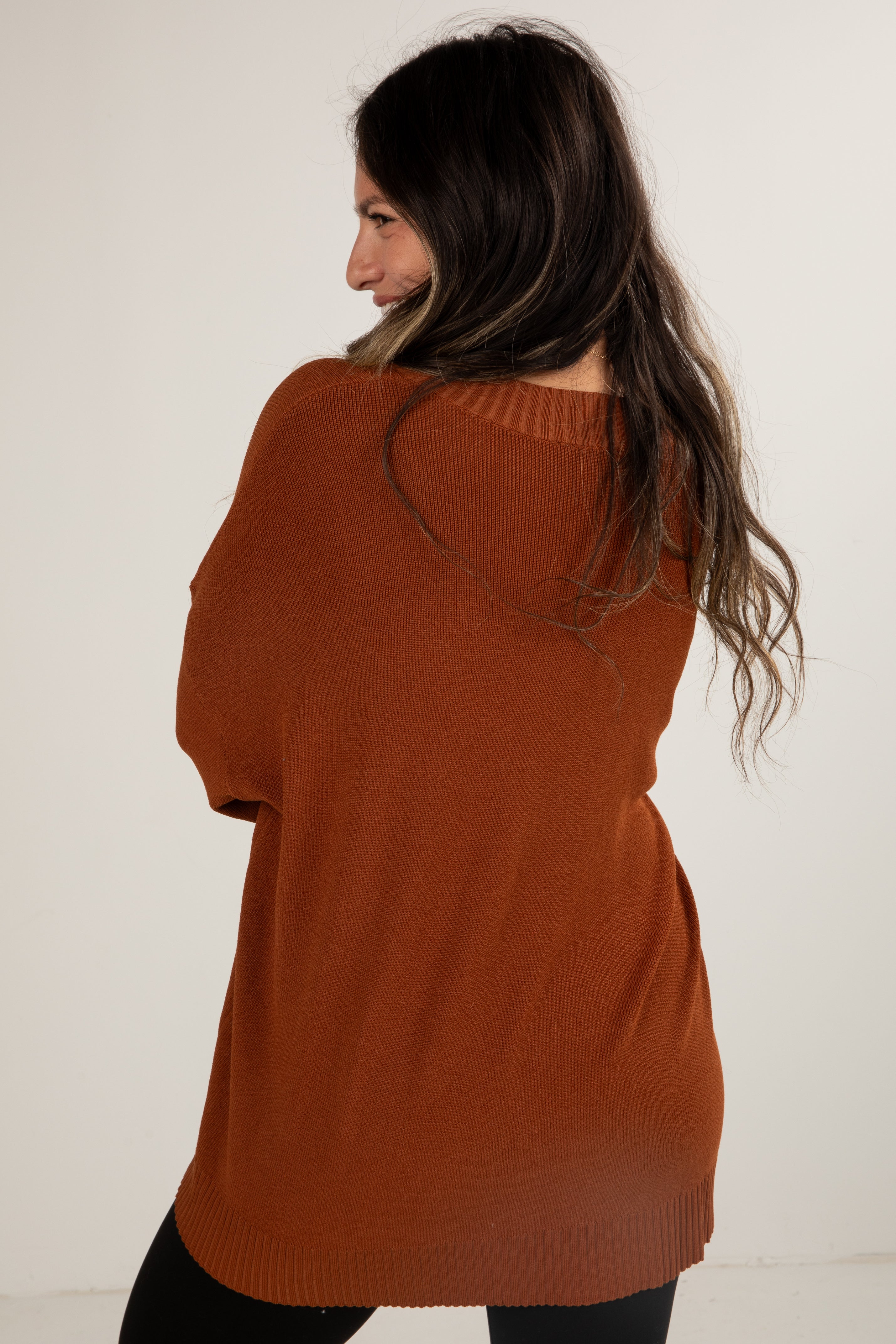 Woman wearing a rust-colored sweater against a white background