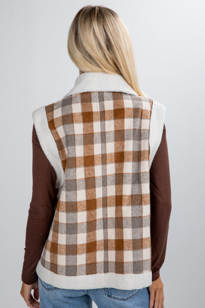Person wearing a plaid vest over a brown long-sleeve shirt on a light gray background