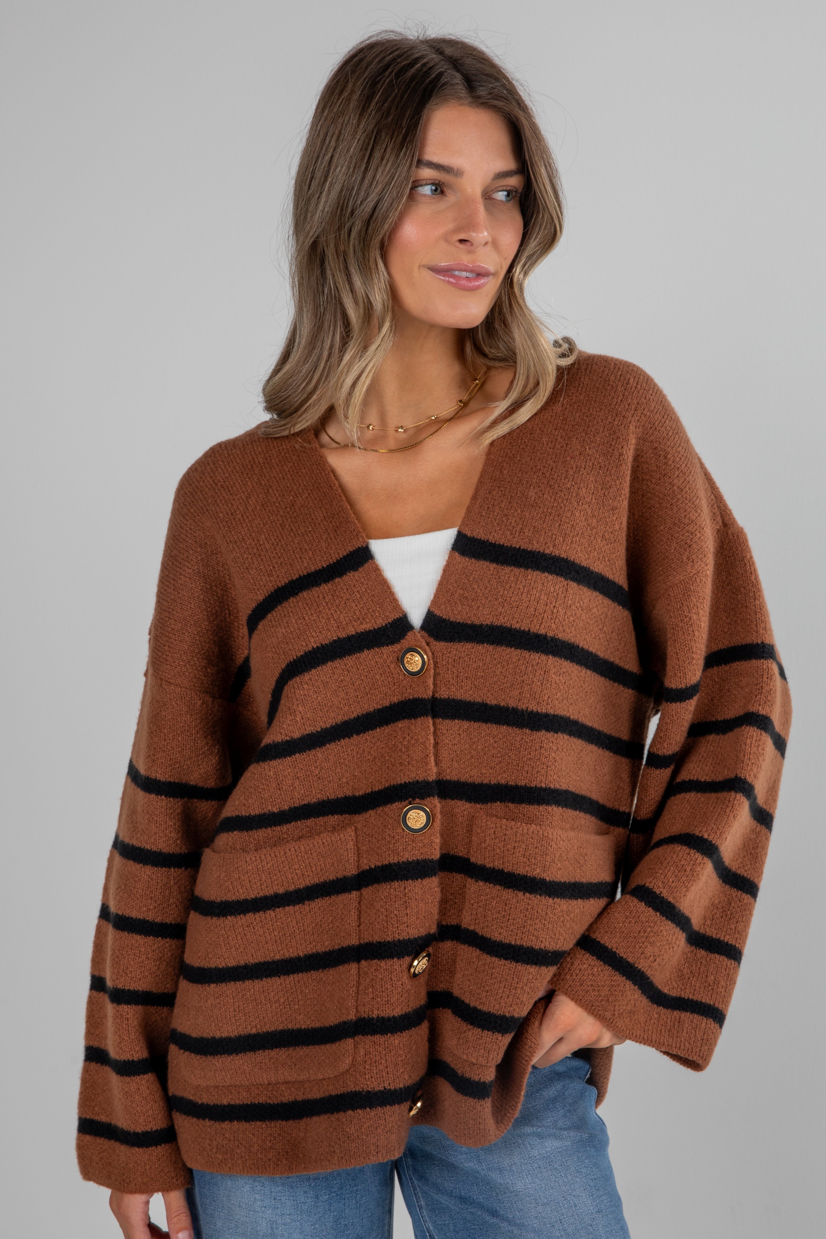 Woman wearing a brown and black striped cardigan on a gray background