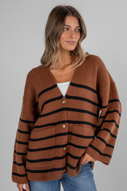 Woman wearing a brown and black striped cardigan on a gray background