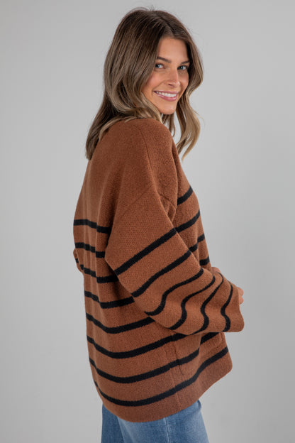 Woman wearing a brown and black striped sweater on a gray background