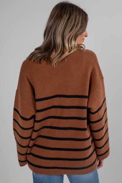 Woman wearing a brown sweater with black stripes on a gray background
