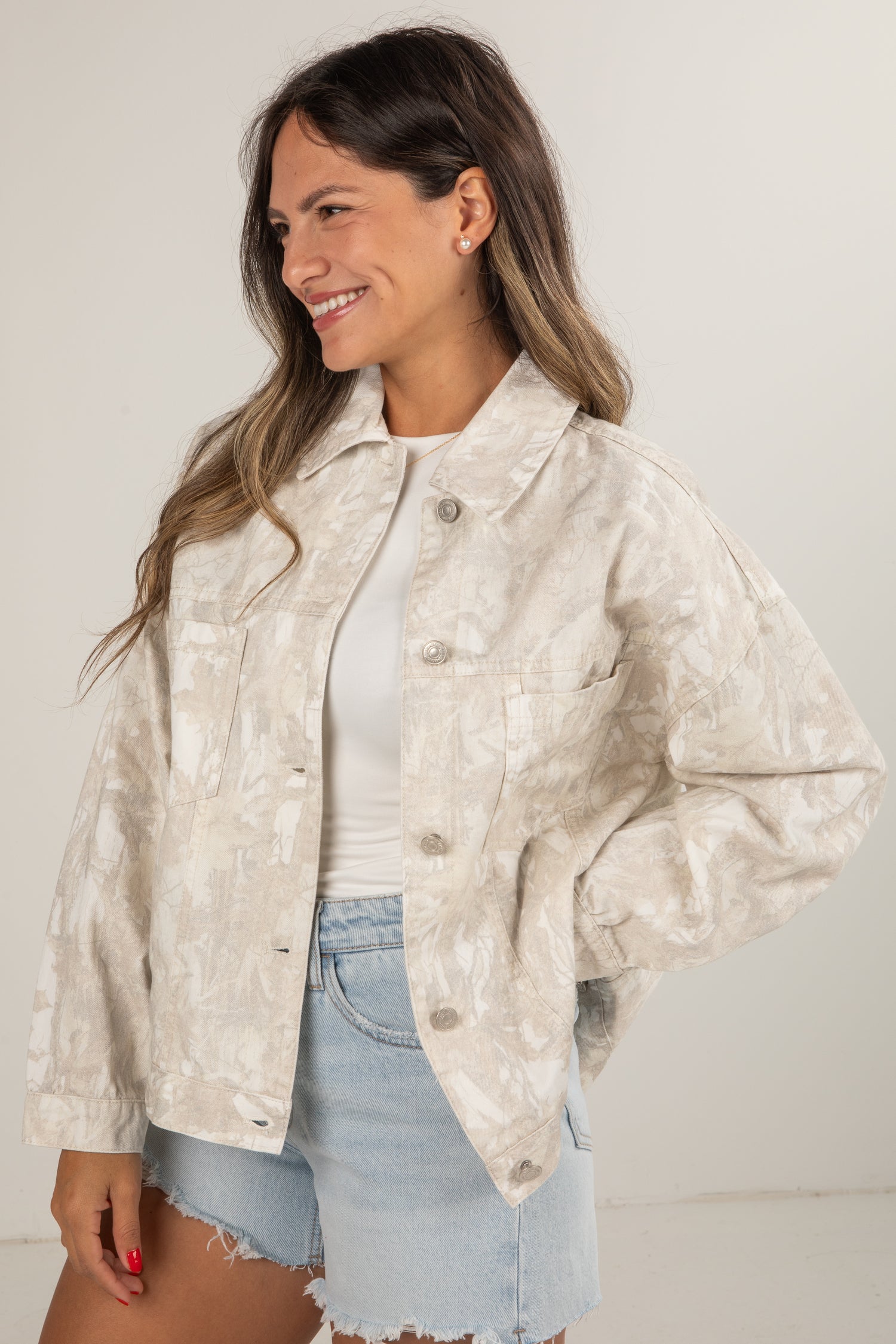 Woman wearing a beige patterned jacket with a plain background