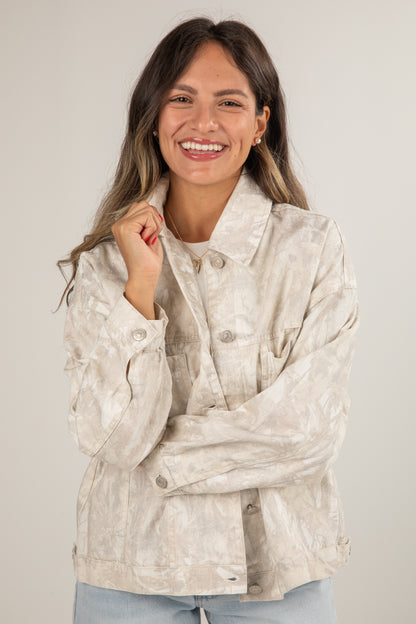 Woman wearing a beige floral jacket against a plain background