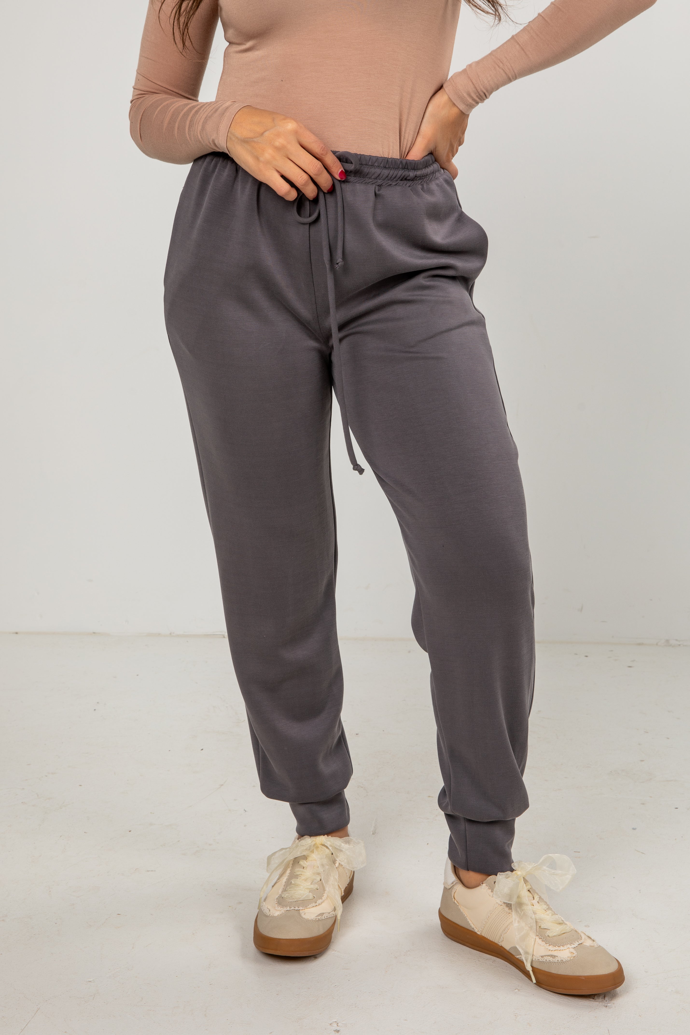 Person wearing gray sweatpants and beige shoes on a white background