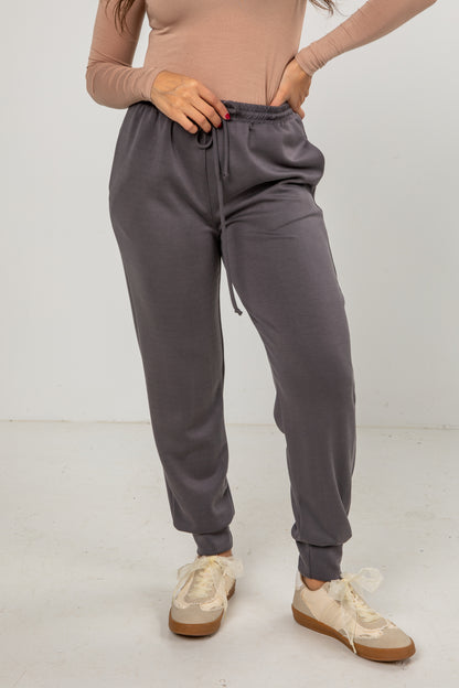 Person wearing gray sweatpants and beige shoes on a white background