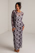 A woman modeling a long-sleeve maxi dress with a gray and black abstract floral pattern, standing in a white studio corner.