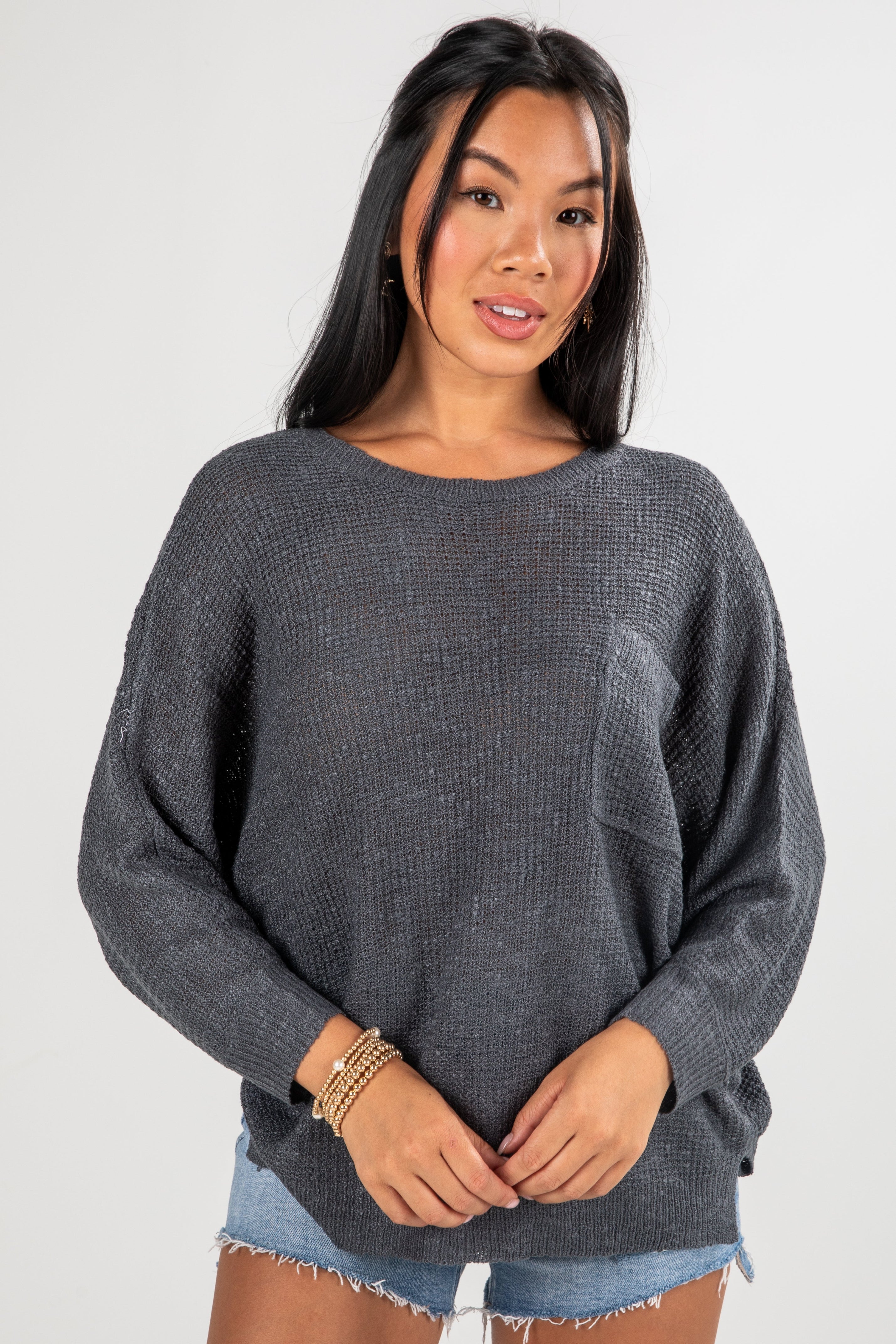 Woman wearing a gray sweater and denim shorts on a white background