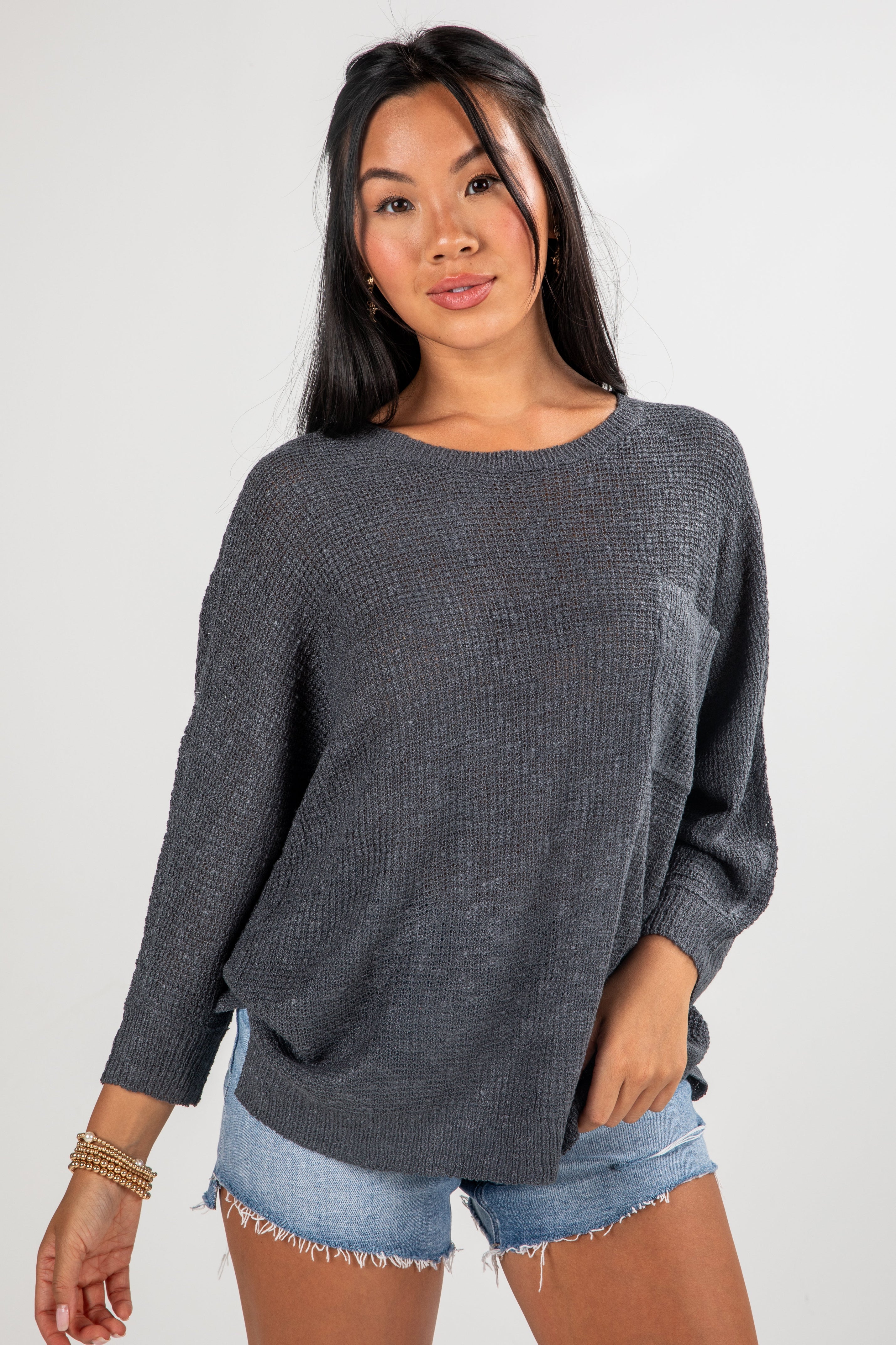 Woman wearing a gray sweater and denim shorts on a white background