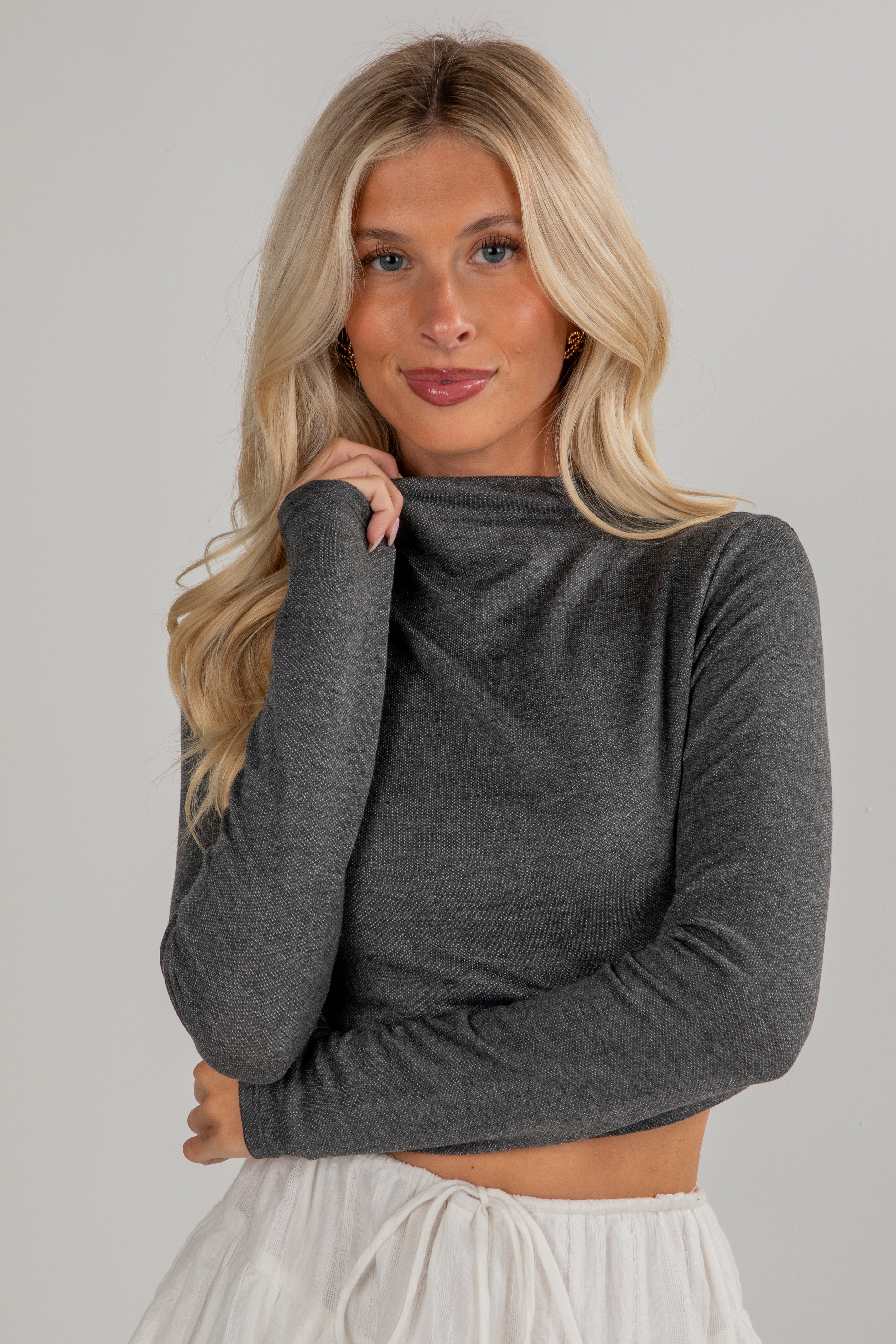 Woman wearing a gray long-sleeve top against a plain background