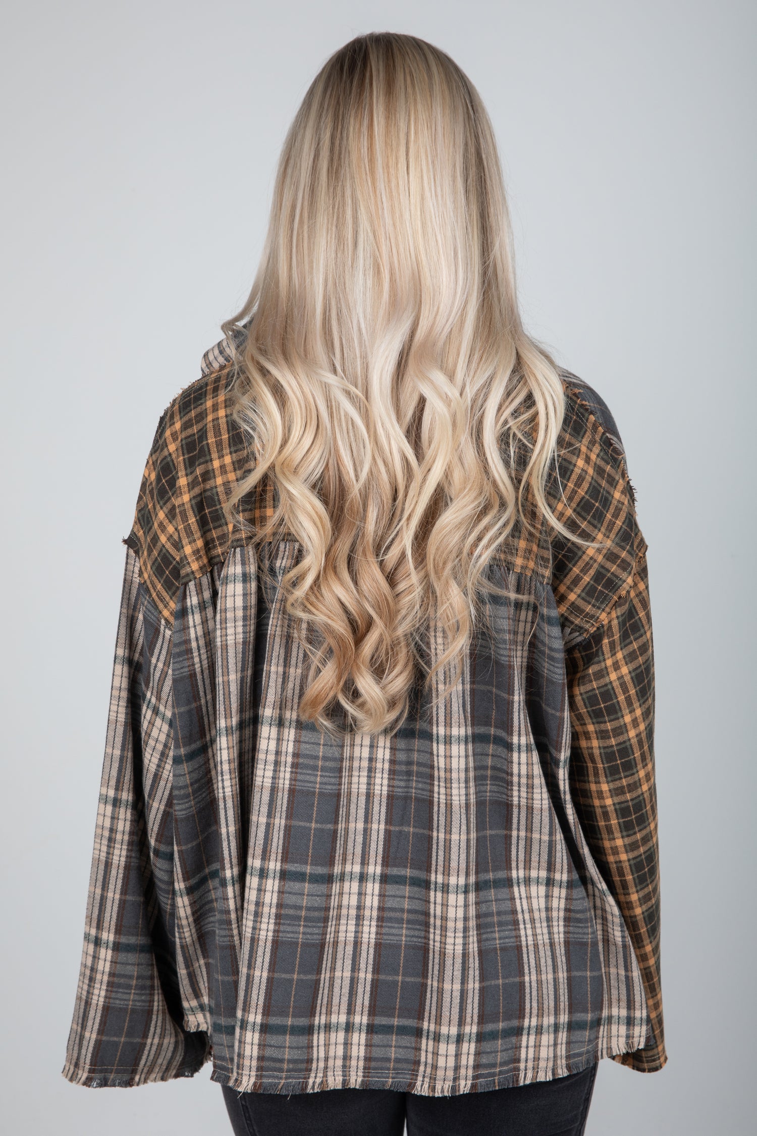 Person wearing a plaid shirt with long blonde hair on a plain background