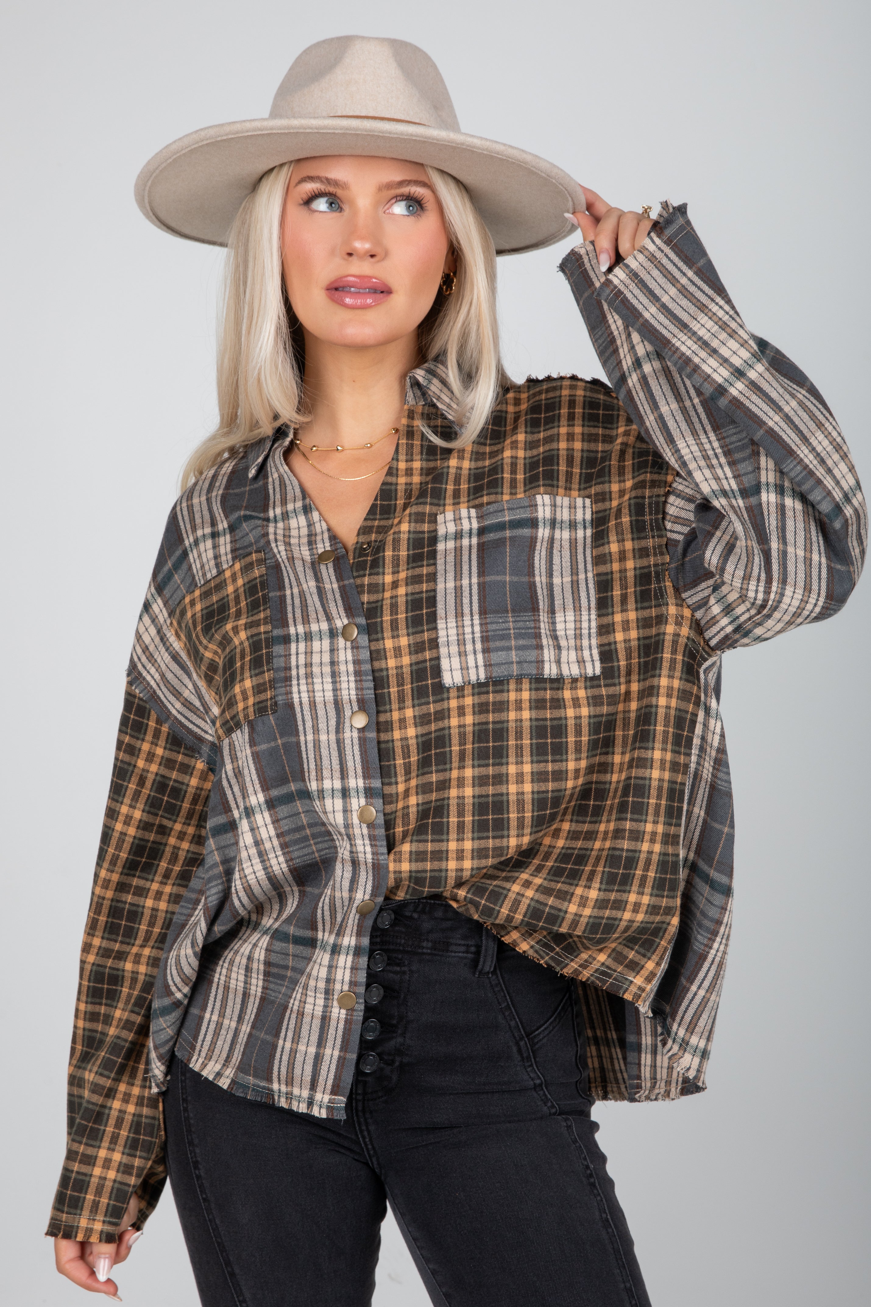 Woman wearing a plaid shirt and hat against a plain background