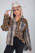 Woman wearing a plaid shirt and hat on a gray background