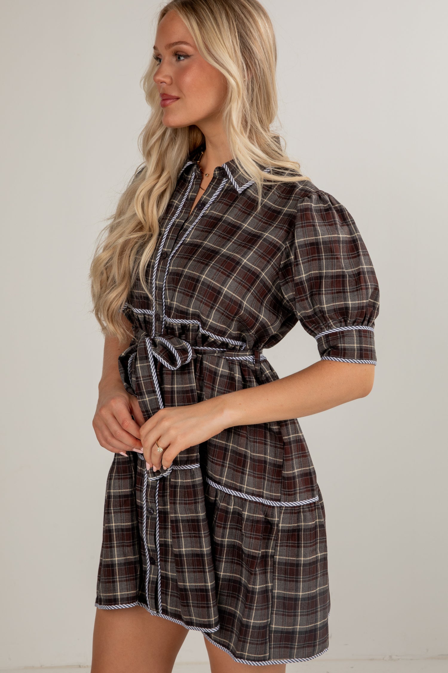 Woman wearing a plaid dress with puff sleeves against a plain background