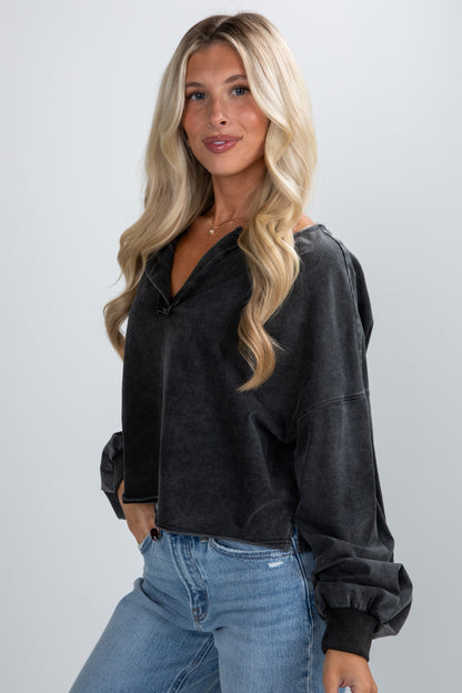 Woman wearing a black pullover and blue jeans against a plain background