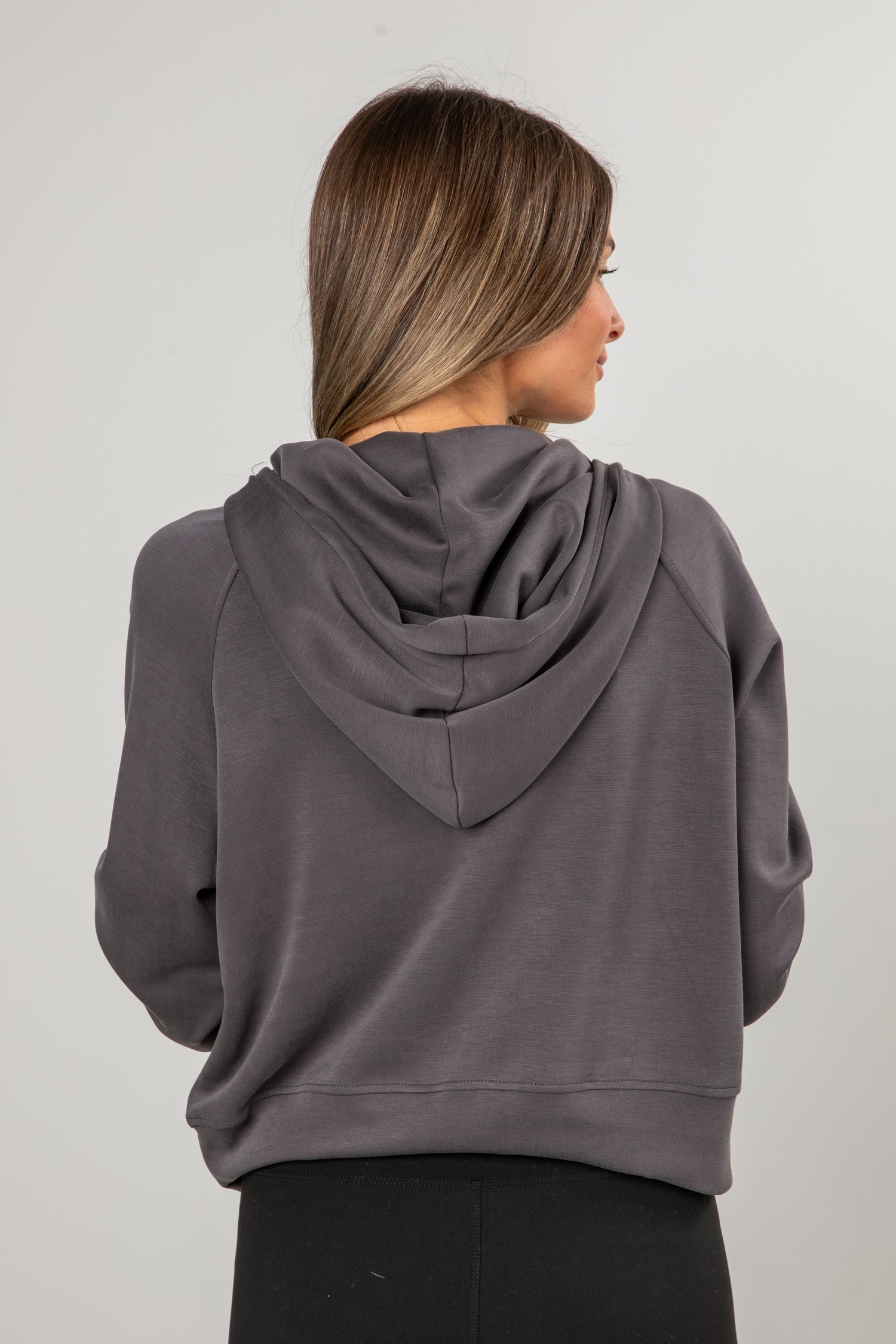 Person wearing a gray hoodie from behind on a plain background