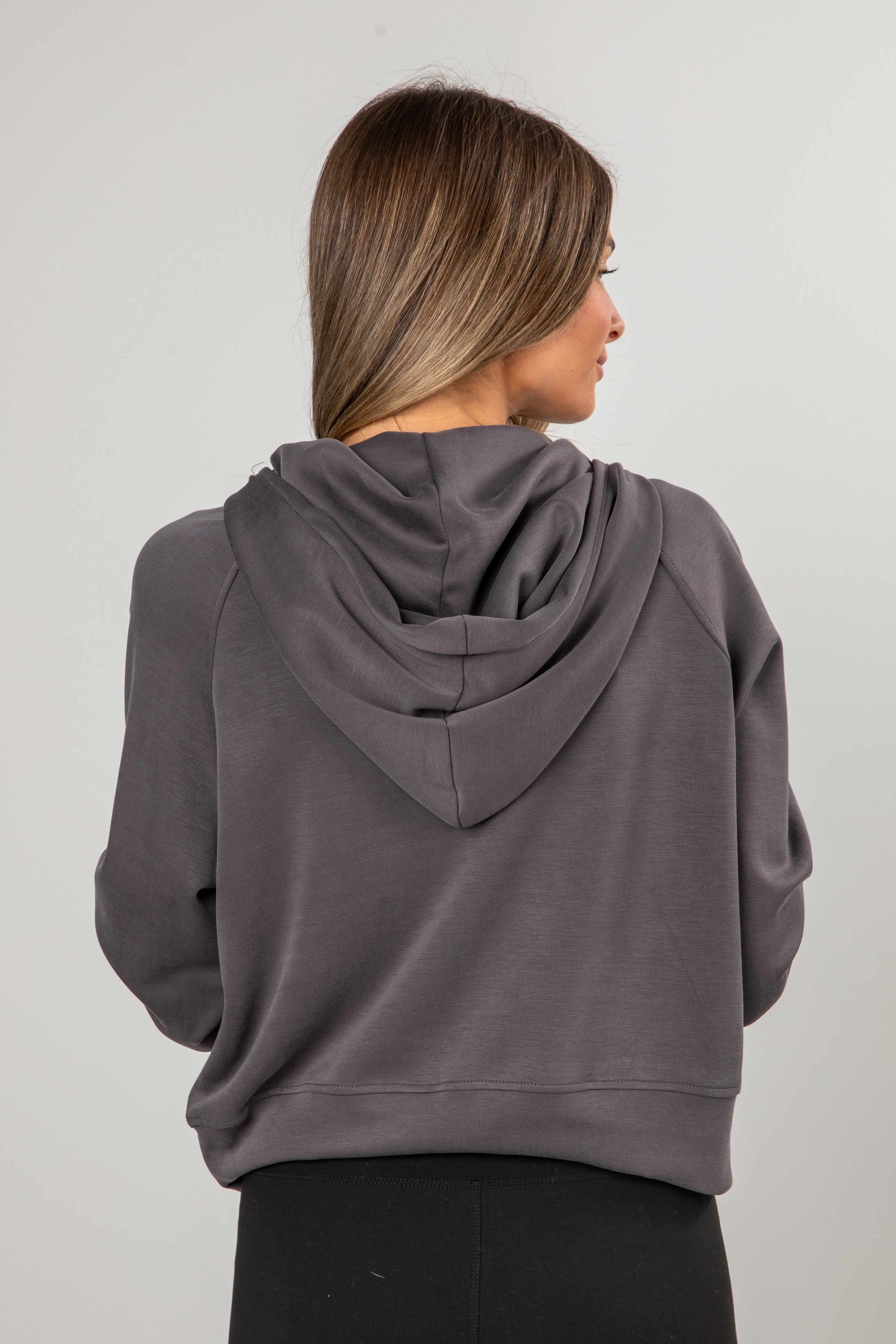 Person wearing a gray hoodie from behind on a plain background